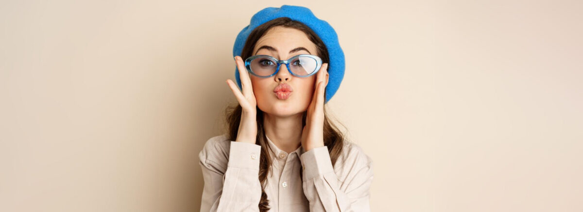 Belle femme élégante dans des lunettes de soleil soufflant un baiser d'air 